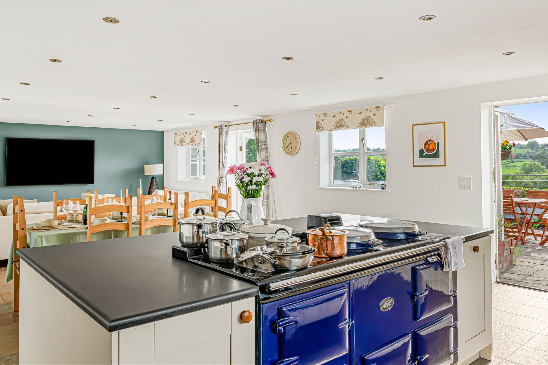 The farmhouse kitchen with blue AGA, dining table and doors to the terrace